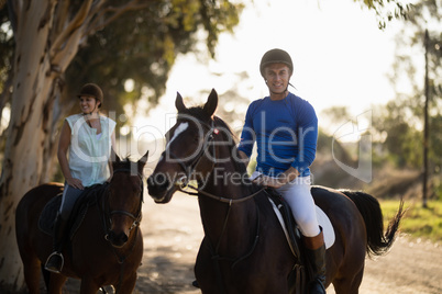 Male trainer with woman riding horse at barn