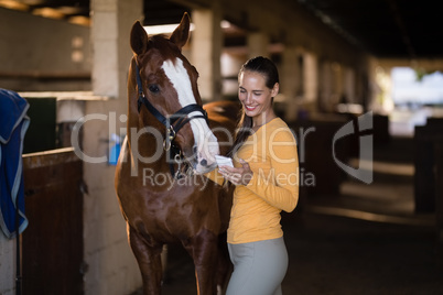 Female jockey using smart phone while standing by horse