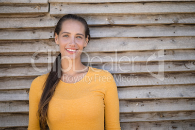 Smiling young jockey standing by wooden wall