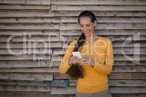 Female jockey using smart phone by stable