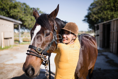 Portrait of smiling female jockey stroking horse