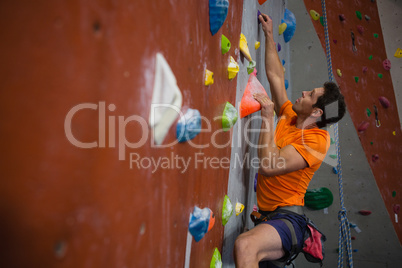 Man wall climbing in gym