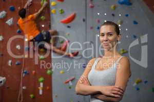 Portrait of confident woman with friend climbing wall in background