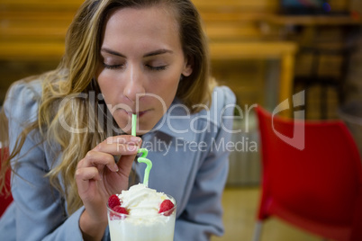 Woman with eyes closed having drink in cafe