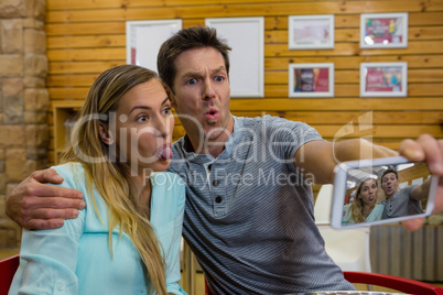 Happy man taking selfie with girlfriend in cafe