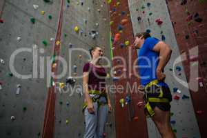 Low angle view of trainer training female athlete in climbing wall