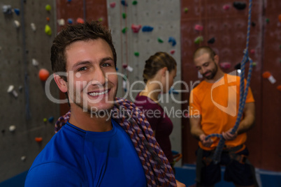 Portrait of man carrying climbing rope in gym