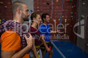 Trainer assisting athletes in wall climbing at club