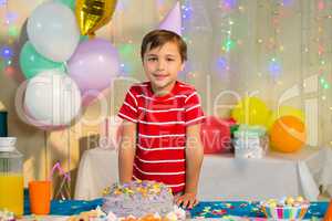 Cute boy standing with birthday cake