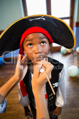 Hand of woman drawing mustache on boy face