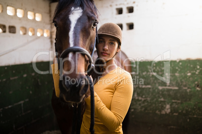 Portrait of female jockey standing by horse