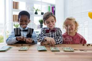 Smiling business people counting money while standing at table in office