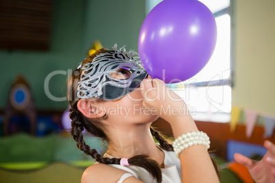 Adorable girl blowing balloon during birthday party