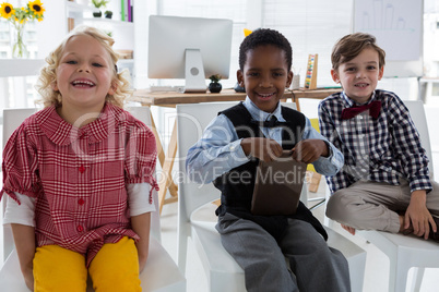 Portrait of happy business people relaxing on chair in office