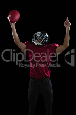 American football player raising hands holding a ball high in one hand