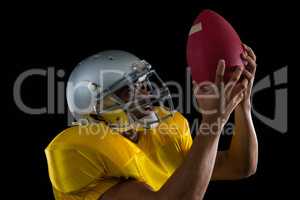 American football player looking at ball holding it in his hands