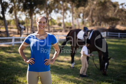 Portrait of female jockey with sister by horse in background
