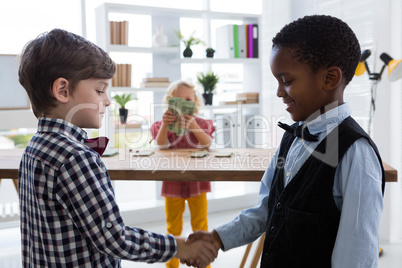 Male colleagues shaking hands while businesswoman counting currency