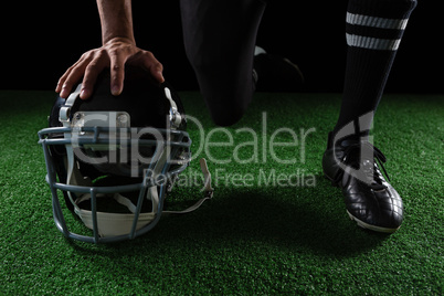 American football player resting his hands on head gear