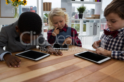 Business people using tablet computers while sitting at table in office