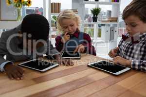 Business people using tablet computers while sitting at table in office
