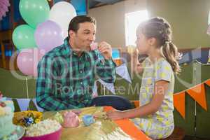 Playful girl and father having tea from the toy kitchen set