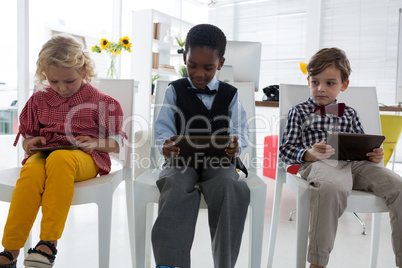 Business people using tablet computers while sitting on chair in office