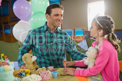 Father and girl interacting while playing toy kitchen set