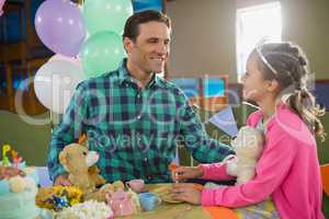 Father and girl interacting while playing toy kitchen set