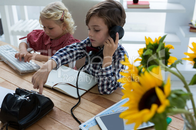 View of businesswoman using computer while male colleague talking on phone in office