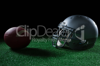 American football head gear and football on artificial turf