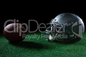 American football head gear and football on artificial turf