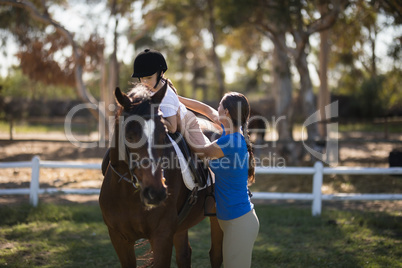 Side view of female jockey assisting sister