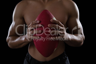 Muscular American football player holding a football in his hand