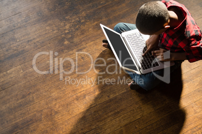 Boy sitting on wooden floor using laptop