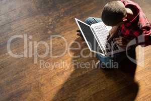 Boy sitting on wooden floor using laptop
