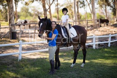 Portrait of smiling jockey and girl with horse