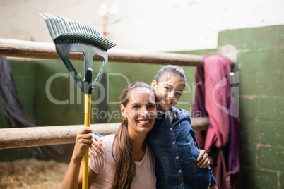 Portrait of female jockey holding rake with sister