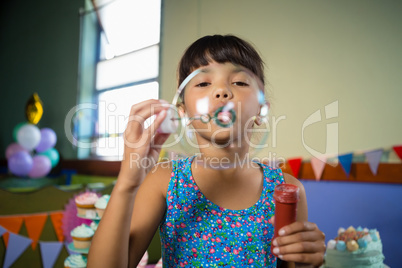 Adorable girl blowing balloon during birthday party