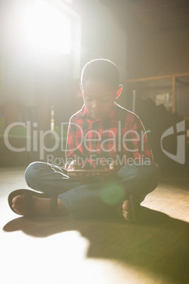 Boy sitting on wooden floor using digital tablet