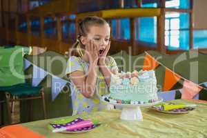 Surprised girl looking at birthday cake