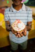 Boy holding decorated cupcake during birthday