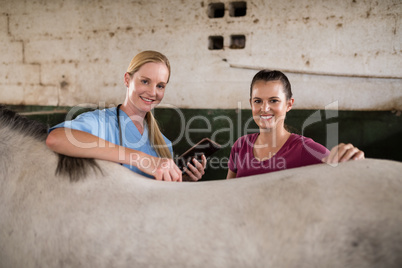 Portrait of female vet with woman standing by horse