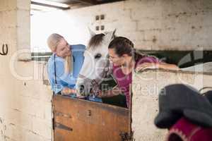 Female vet with woman looking at horse