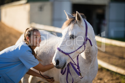 Smiling female vet checking horse