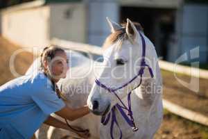 Smiling female vet checking horse