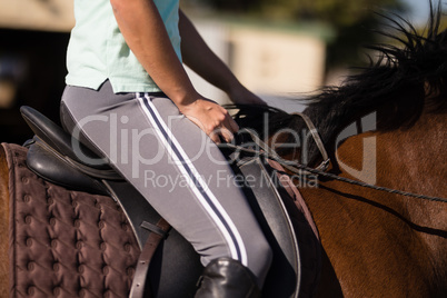 Mid section of female jockey sitting on horse