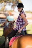 Portrait of woman horseback riding with friend sitting on horse in background