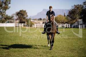 Portrait of confident female jockey riding horse at barn