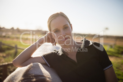 Confident female jockey standing by horse at barn